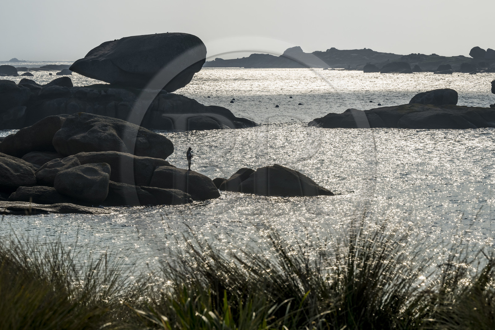 France, Côtes-d'Armor (22), Côte de Granit Rose, Trégastel, jeune pecheur à la ligne sur les rochers devant la plage de Ker ar Vir que longe le chemin de Grande Randonnée GR 34