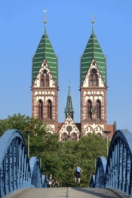 Germany, Baden-Wurttemberg, Freiburg im Breisgau, cyclist on the blue bridge (wiwili-bridge) and the Sacred Heart of Jesus Church (Herz-Jesu-kirche) in the background