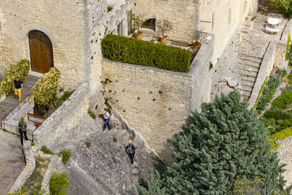 France, Vaucluse (84), Dentelles de Montmirail, le village perché de Crestet, montée de randonneurs sur le sentier à fleur de roche le long de son chateau du IXe siècle (vue aérienne)