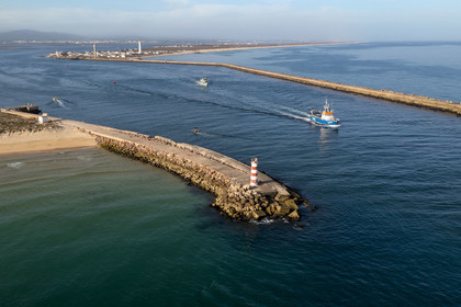Portugal, Algarve, Parc naturel de la Ria Formosa, Faro, l'Ile de Barreta ou Deserta (Ilha da Barretta ou Deserta) bateau de pêche sortant du port, le phare de Ilha do Farol sur Ilha da Culatra en arrière plan (vue aérienne)