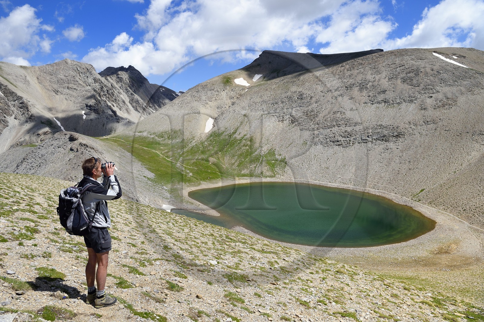 France, Alpes-de-Haute-Provence (04), Uvernet-Fours, parc national du Mercantour, vallée de l'Ubaye, sentier de randonnée du circuit des lacs du col de la Cayolle, garde du parc en observation au-dessus du lac de Garrets
