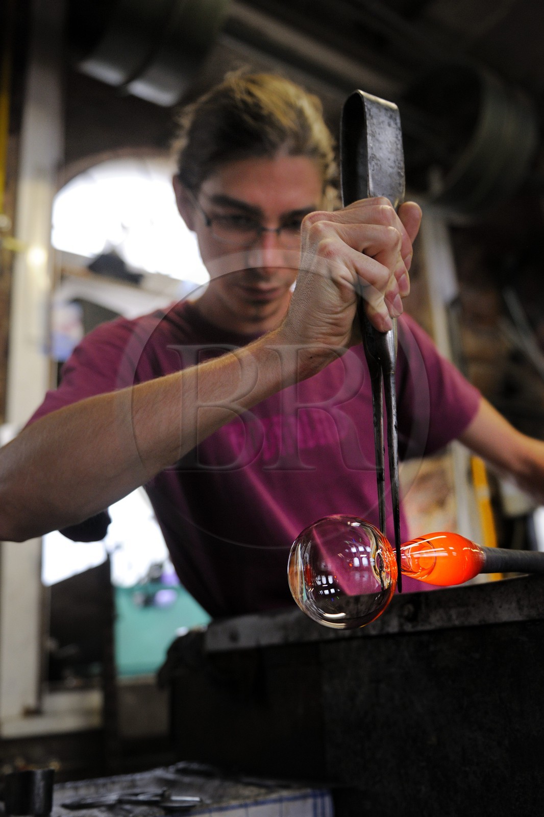 France, Moselle (57), Meisenthal, souffleur au Centre international d’Art verrier (CIAV), fabrication d'une boule de Noël en verre. La canne de verre posée sur un banc appelé « gamin mécanique », Thibaut crée avec la pince l’étranglement