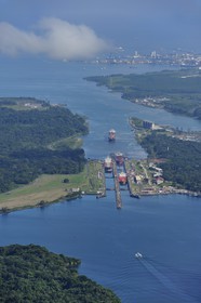 Panama, province de Colon, Canal de Panama, cargo Panamax passant les écluses de Gatun, la baie Limon (Bahia Limon) coté Atlantique et la ville de Colon en arrière plan (vue aérienne)