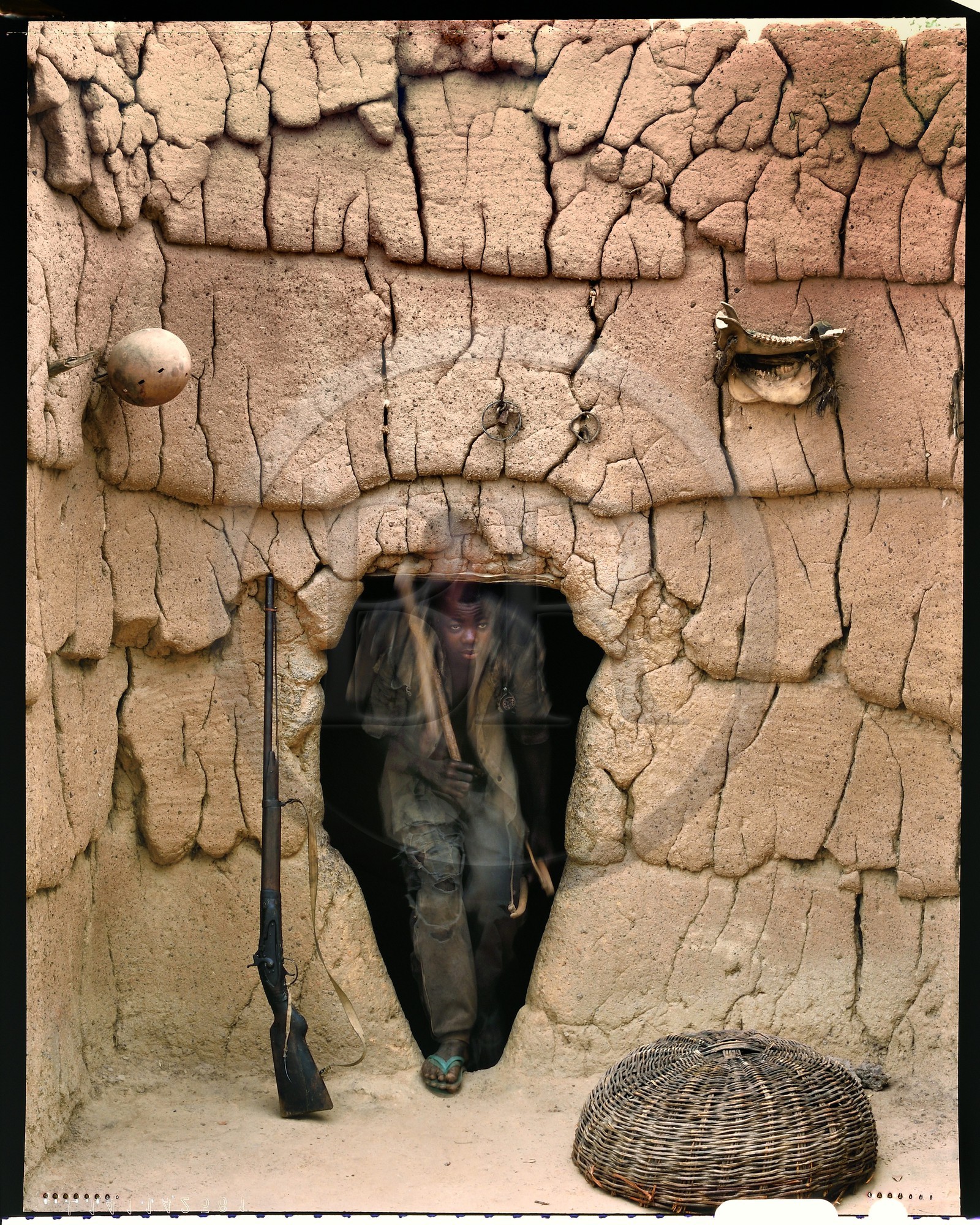 Burkina Faso, province de Poni, pays des Lobi, Loropéni, jeune Lobi sortant de la maison de son père avec les attributs des initiés: l'arc, le carquois et la houe