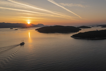 Croatia, Dalmatia, Dalmatian coast, boat sailing at dawn towards archipelago Skoji in the strait between the Peljesac peninsula and Korcula Island (aerial view)