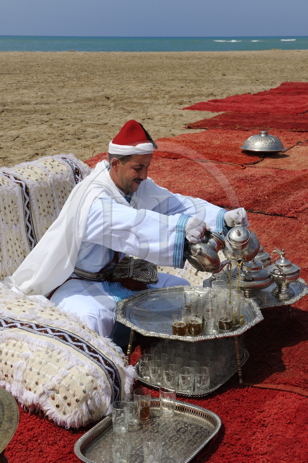 Maroc, région de l'Oriental, service du thé à la menthe en costume d'apparat sur une plage