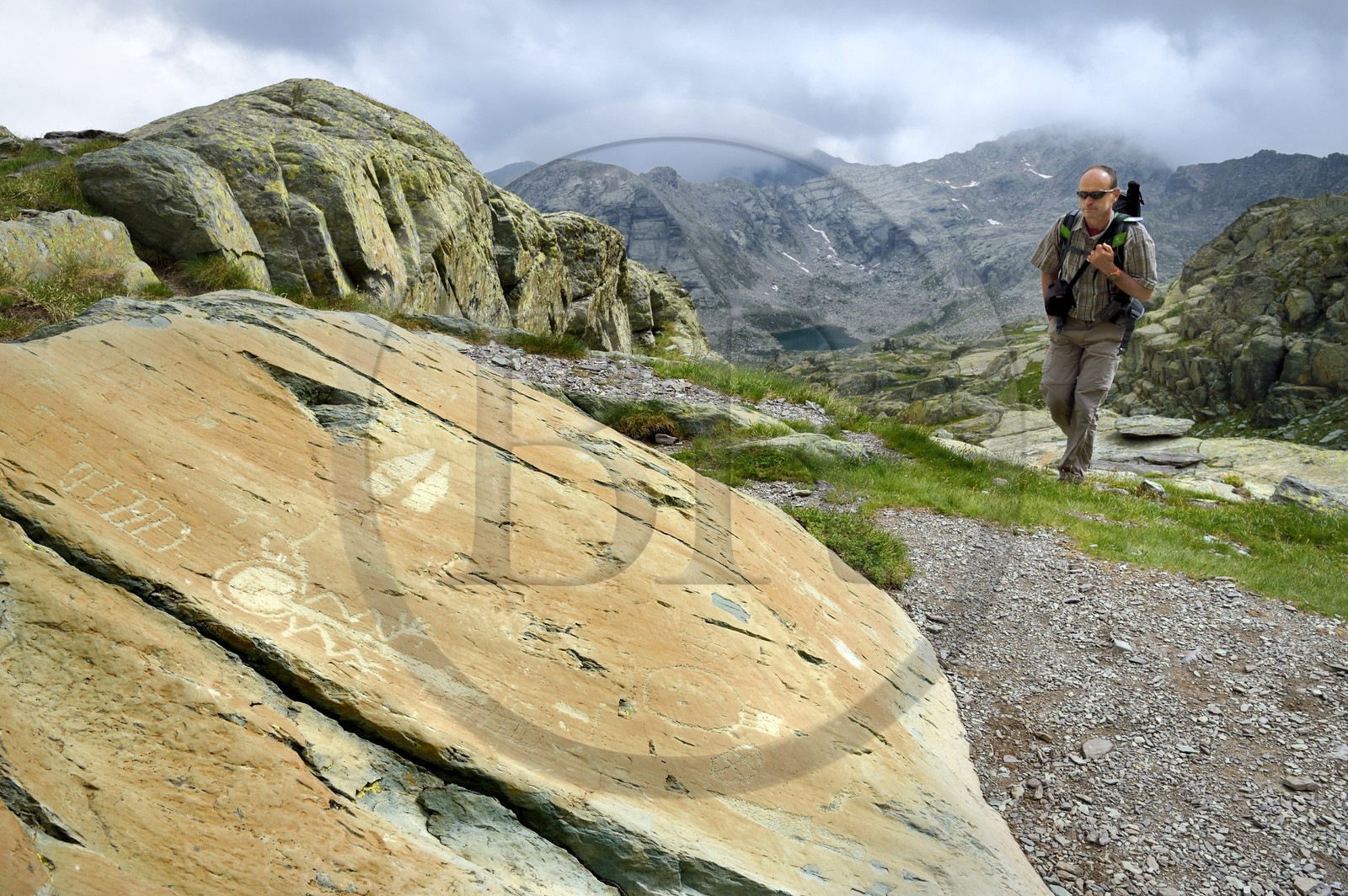 France, Alpes-Maritimes, parc national du Mercantour (Mercantour National Park), the Vallee des Merveilles (Valley of Wonders) scattered with thousands of rupestral engravings of the Bronze Age, Pas de l'Arpette (Arpette pass), hiker approaching the engraving called the zigzag arm Anthropomorphous, a checkerboard-like figure that could symbolize cultivated fields left and two daggers