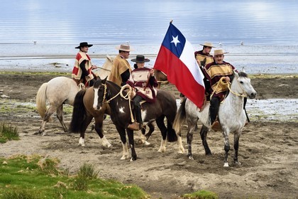Chili, région de Los Lagos, archipel de Chiloé, Ile de Quinchao, Curaco de Velez, huasos (cavaliers) avec chupalla et manta avant un défilé, une jeune fille huaso porte le drapeau chilien