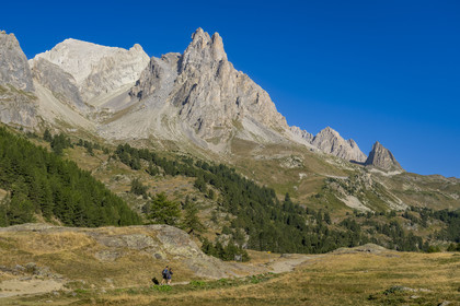 France, Hautes Alpes (05), le Briançonnais, Névache, randonneurs dans la vallée de la Clarée, le massif des Cerces et les pointes de la Main de Crépin (2942m) en arrière-plan