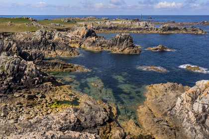 France, Finistère (29), Mer d'Iroise, Ile d'Ouessant, rochers façonnés par les tempêtes au pied du phare du Créac’h, le phare de Nividic sur la Pointe de Pern en arrière plan (vue aérienne)