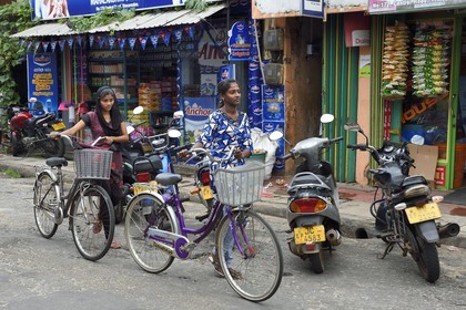 Sri Lanka, province de l'Est, Trincomalee, jeunes filles à bicyclettes devant des commerces de la rue principale