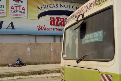 Tanzanie, Dar es-Salaam, vendeur de casquettes sur le trottoir et affiche de Barack Obama à l'arrière d'un bus