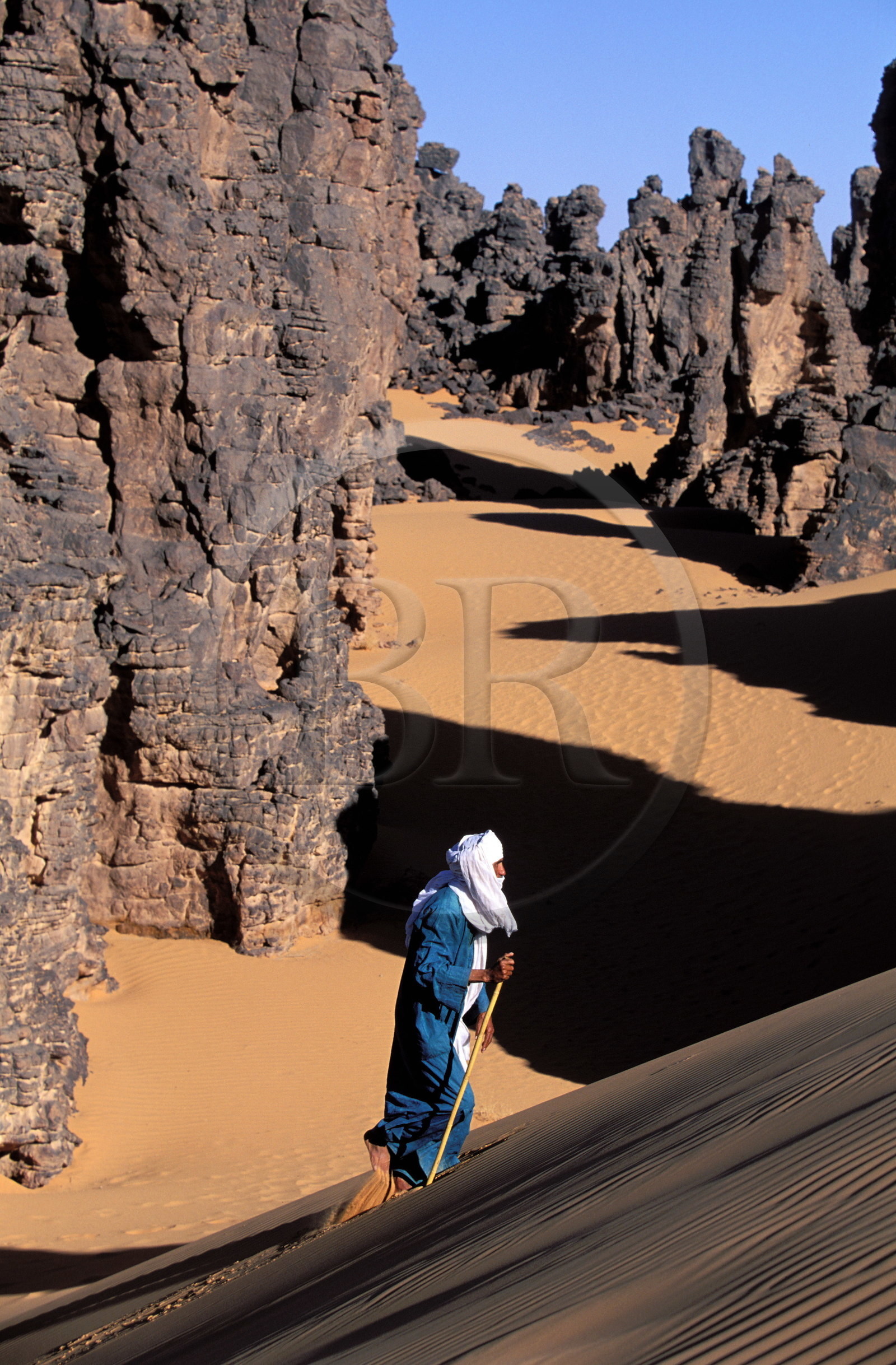 Libye, région du désert, Le Fezzan (Sahara), Touareg marchant entre les aiguilles de grès du Tassili de Maghidet (frontière algérienne)