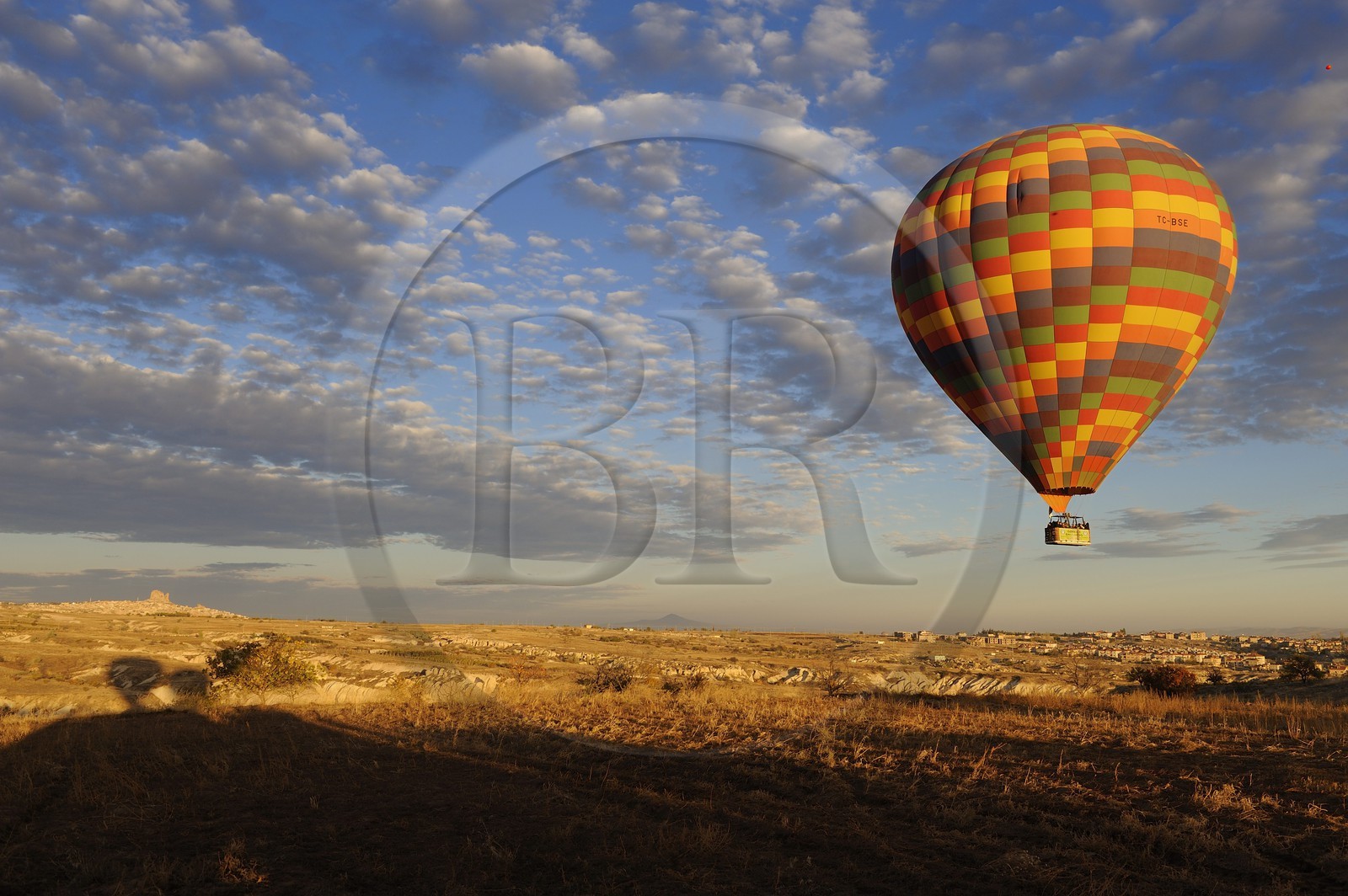 Turquie, Anatolie Centrale, province de Nevsehir, Cappadoce classée Patrimoine Mondial de l'UNESCO, vol d'une montgolfière avec le rocher d'Uçhisar au fond