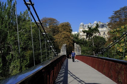 France, Paris (75), parc des Buttes Chaumont, la passerelle suspendue et les immeubles haussmanniens de la rue Manin