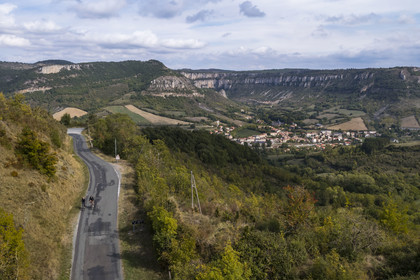 France, Aveyron, Grands-Causses Regional Nature Park, cyclistes effectuant l'itinéraire cyclo touristique Brebis'Cyclette en Pays de Roquefort, the village of Tournemire in the cirque at the foot of the Causse du Larzac (aerial view)
