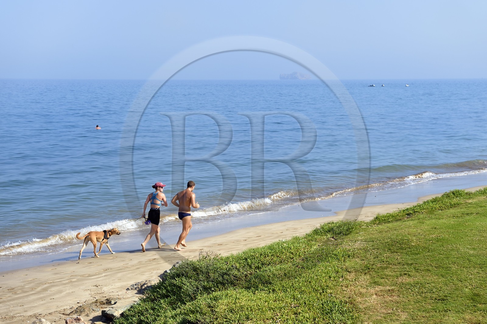 Sultanat d'Oman, Mascate, couple avec un chien courant sur la plage de la Madinat Al Sultan Qaboos