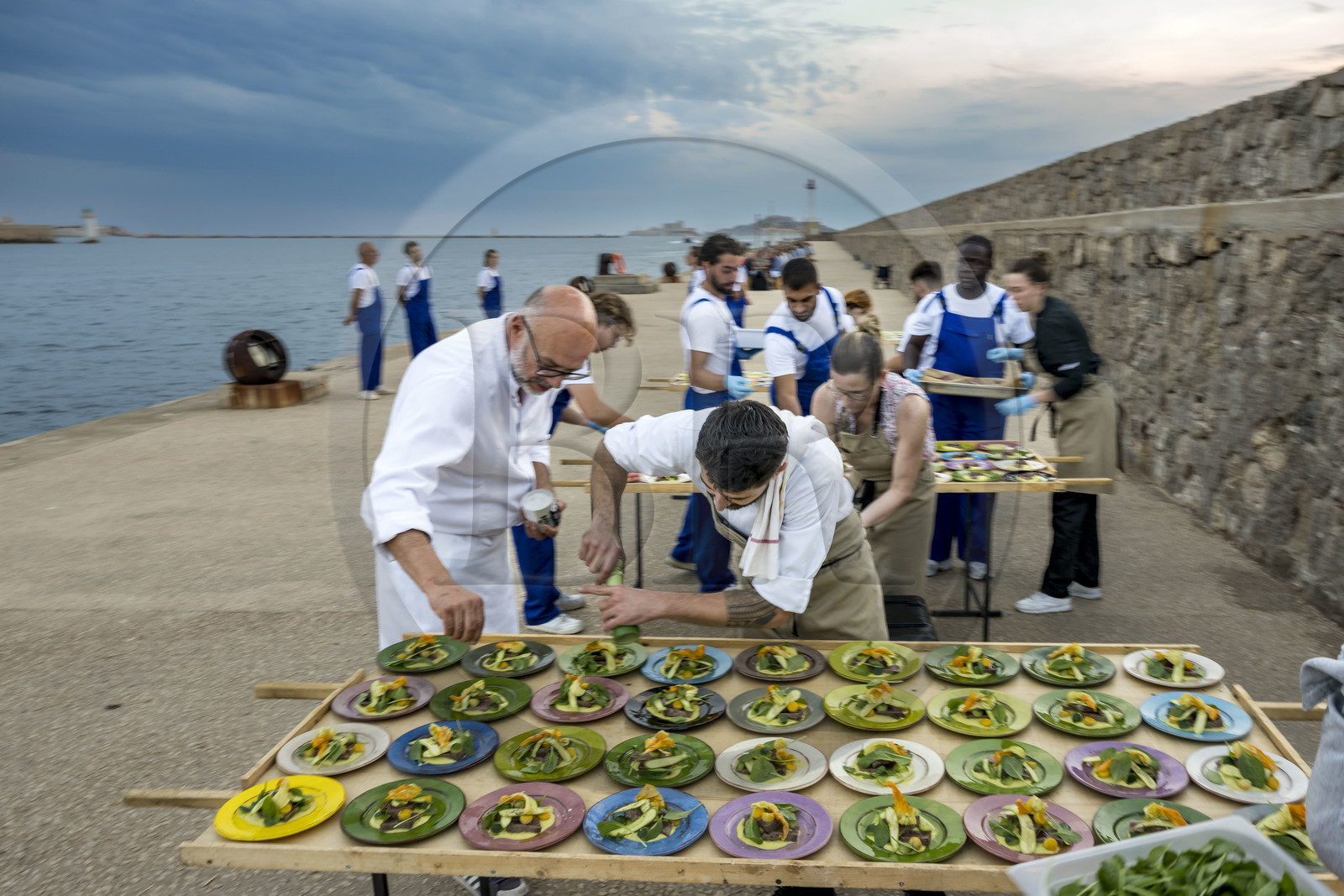 France, Bouches-du-Rhône (13), Marseille, Zone Euroméditerranée, grand port maritime de Marseille (GPMM), la digue du large, convives attablés à une grand table de banquet dressée par le chef Emmanuel Perrodin dans le cadre des Diners Insolites, derniers préparatifs au plats