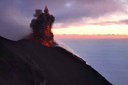 Italie, Sicile, iles Eoliennes, classées Patrimoine Mondial de l'UNESCO, ile de Stromboli, éruption et projection de bombes de lave sur les pentes du volcan actif au coucher de soleil