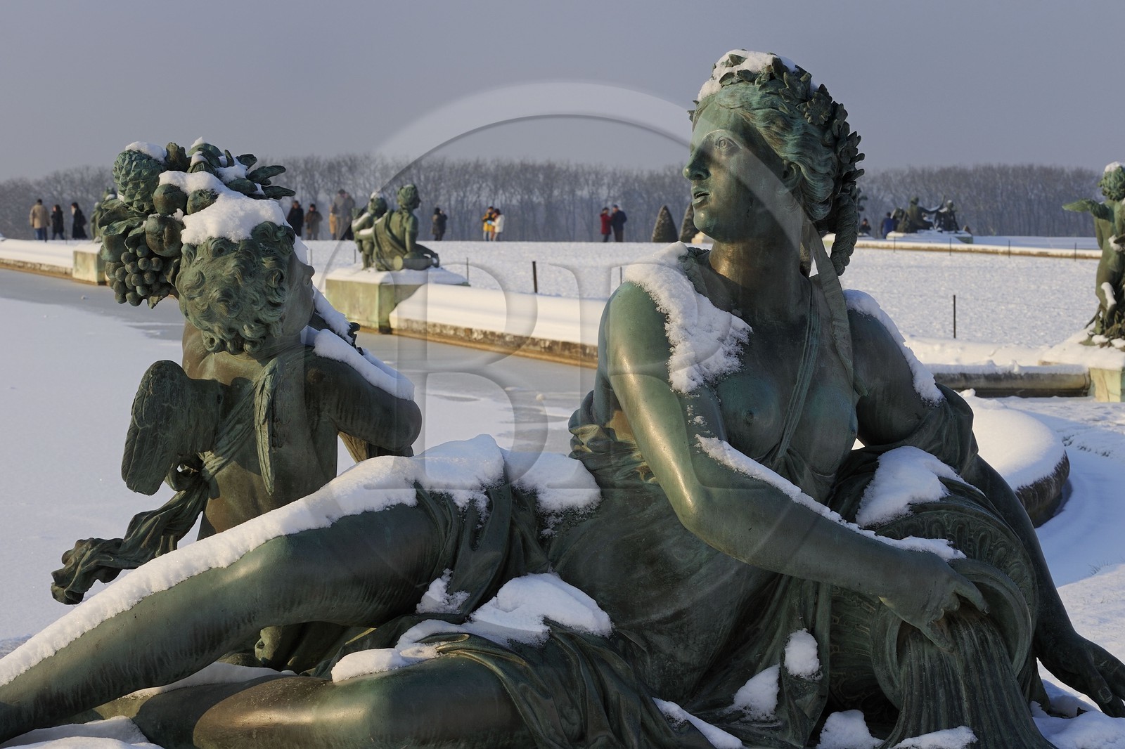 France, Yvelines, snow covered park of the Chateau de Versailles, listed as World Heritage by UNESCO, statue on the Parterre d'eau