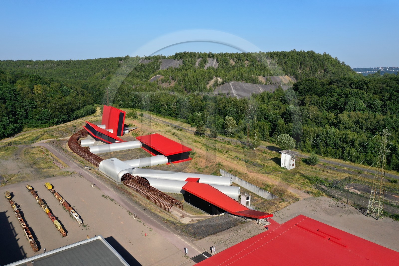 France, Moselle (57), Petite-Rosselle, le musée du carreau Wendel, les batiments construits pour héberger la reconstitution des différents types de veines de charbon de la mine et se présentent sous la forme d’un grand livre ouvert rouge qui symbolise l’histoire de la mine, terrils en arrière plan (vue aérienne)
