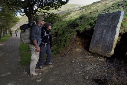 France, Pyrénées-Atlantiques (64), Pays-Basque, chemin de Saint-Jacques de Compostelle sur le GR 65 entre Saint-Jean-Pied-de-Port et Roncevaux vers le col de Bentarte, pèlerins devant la stèle indiquant que Compostelle est encore à 765 km