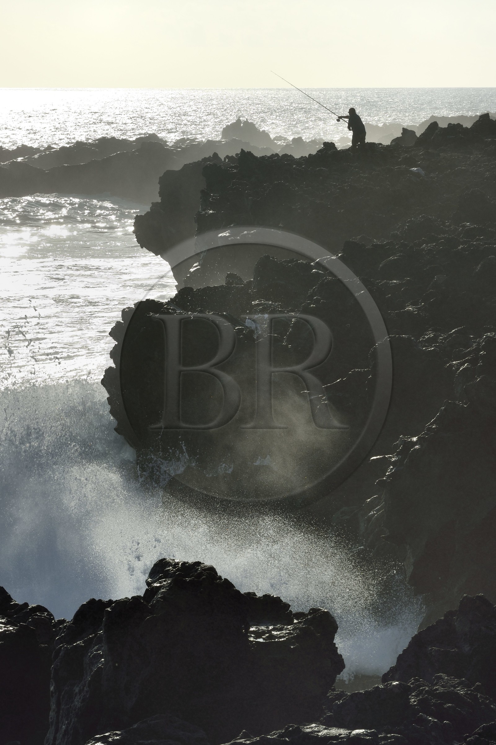 France, Ile de la Reunion, L'Etang Salé les Bains, la côte entre Le Gouffre et l'Etang du Gol, roches noires basaltiques d'origine volcanique tourmentées par l'océan, pêcheur à la ligne