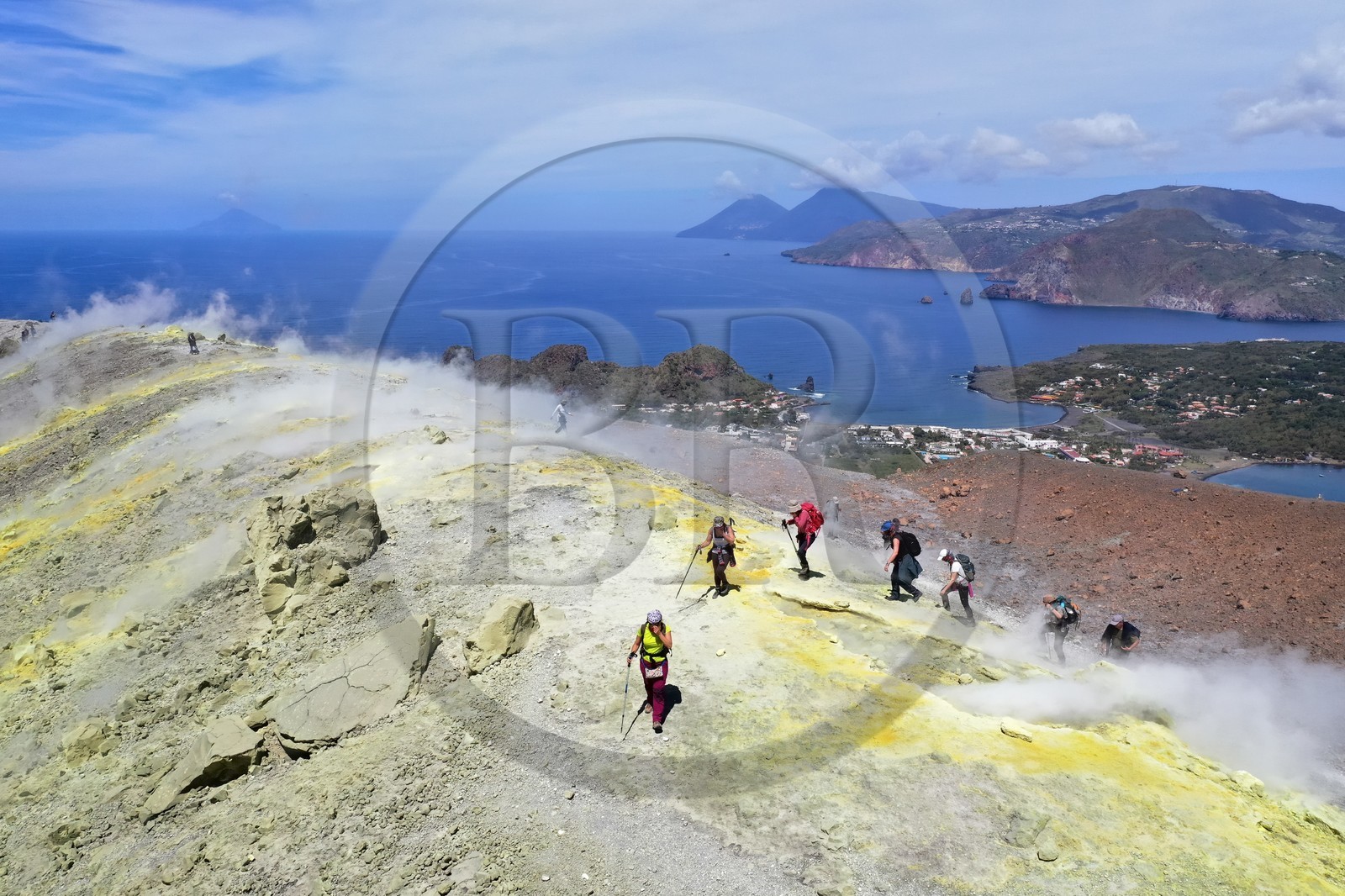 Italy, Sicily, Aeolian Islands, listed as World Heritage by UNESCO, Vulcano Island, hikers climbing the crater of volcano della Fossa walking through sulfur fumaroles, the island of Lipari then Salina island in the background (aerial view)