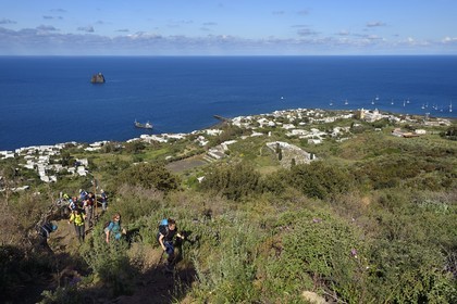 Italie, Sicile, iles Eoliennes, classées Patrimoine Mondial de l'UNESCO, ile de Stromboli, randonneurs commençant l'ascension du volcan, le village de Stromboli et l'ilot de Strombolicchio en arrière plan