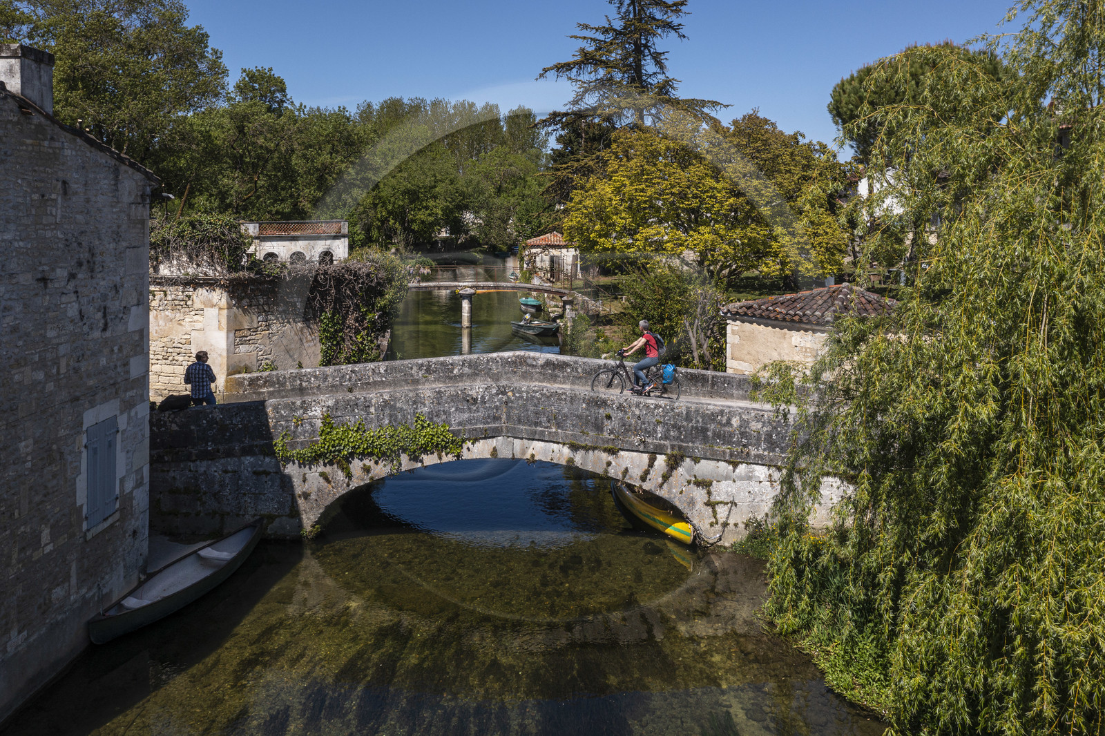 France, Charente (16), Bassac, cycliste faisant la véloroute La Flow Vélo passant le pont sur la Guirlande, un petit affluent du fleuve La Charente qui traverse le pied du bourg (vue aérienne)
