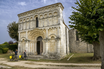 France, Charente Maritime, Echillais, cyclists traveling along the cycle route in front of the 12th century Romanesque church of Notre-Dame, classified as a historic monument