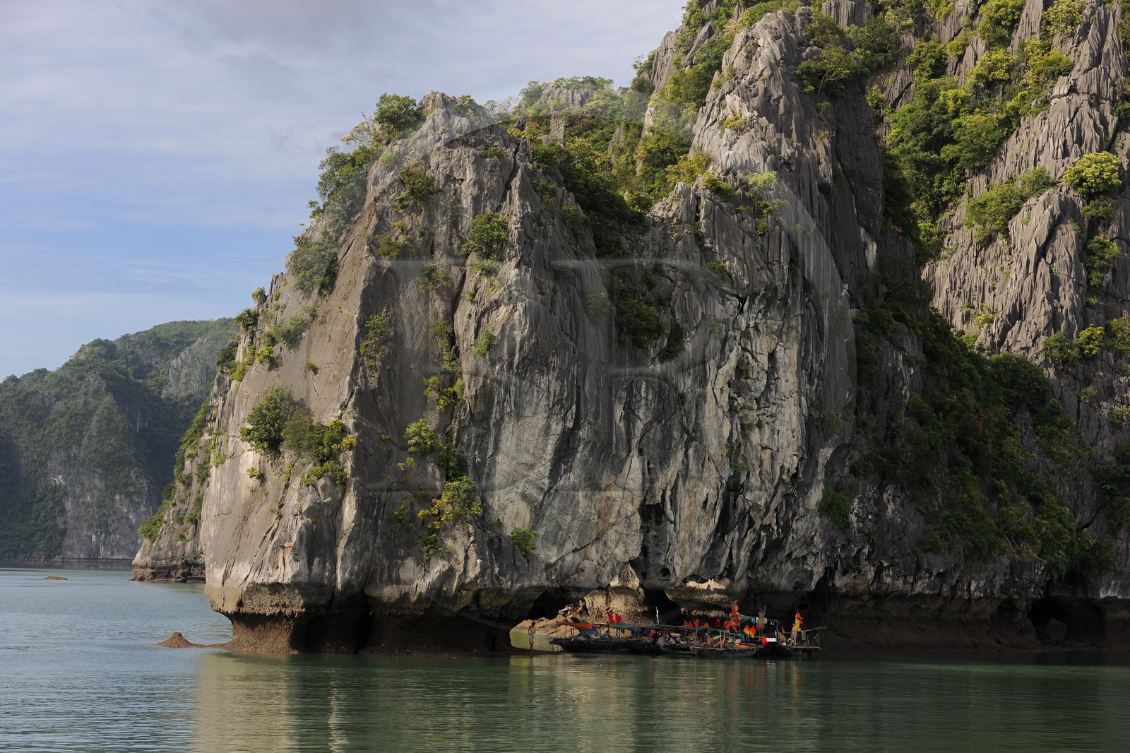 Vietnam, province de Quang Ninh, la Baie d'Halong classée Patrimoine Mondial de l'UNESCO, regroupement de bateaux de pêche sous une arche naturelle d'un ilot calcaire