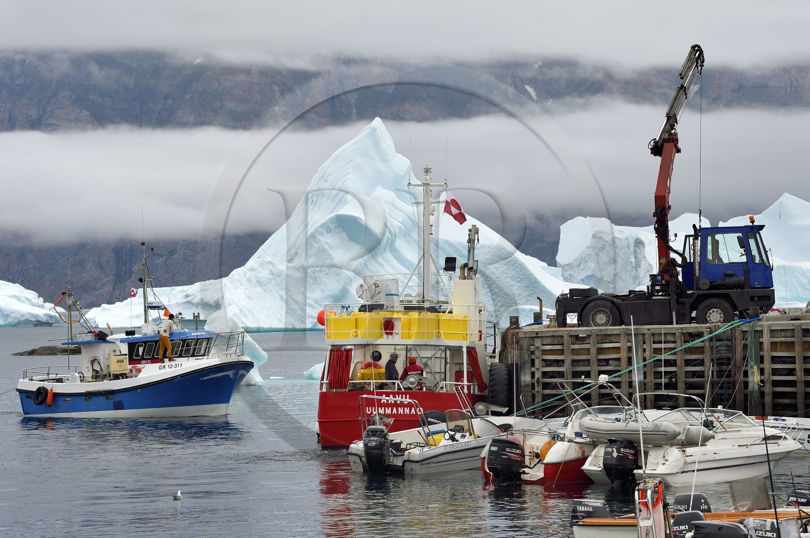 Groenland, cote ouest, Uummannaq, bateau de pêche déchargeant dans le port et icebergs en arrière plan