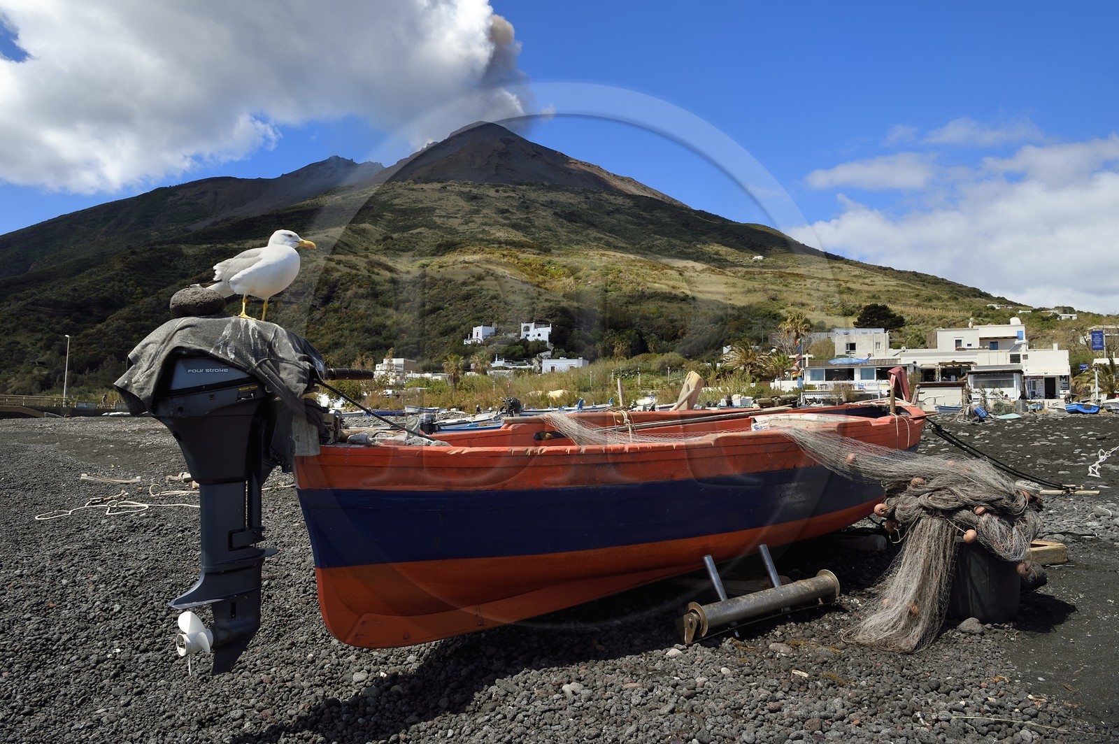 Italy, Sicily, Aeolian Islands, listed as World Heritage by UNESCO, Stromboli island, one of the multiple and regular eruptions of the Stromboli volcano which rises to 924m, fishing boat on the beach of Scari in the foreground