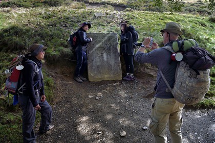 France, Pyrenees Atlantiques, Basque Country, Camino de Santiago (the Way of St. James) on the GR 65 between Saint Jean Pied de Port and Roncesvalles towards the Bentarte Pass, pilgrims in front of the stele indicating that Compostela is still 765 km