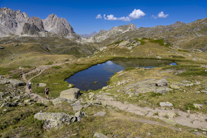 France, Hautes Alpes, Briancon region, Nevache, the upper Clarée valley, hikers at the small lake between Lac Long and Lac Rond, the Cerces massif in the background