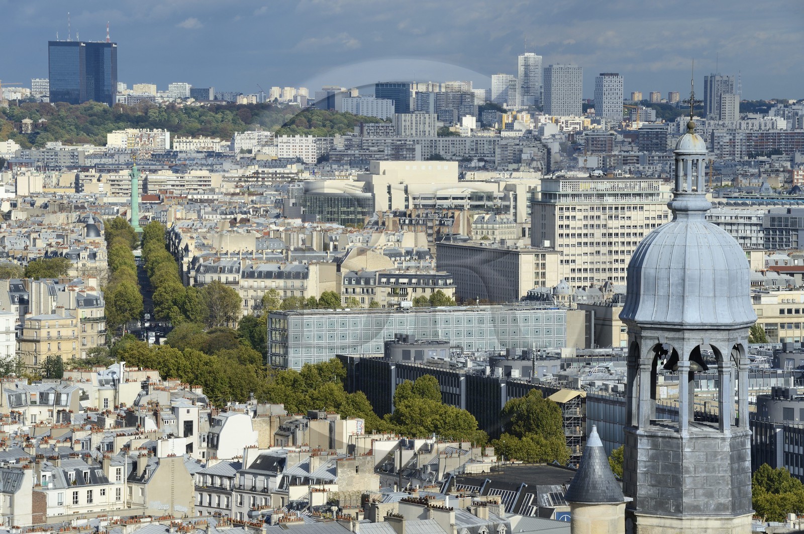 France, Paris, the bell tower of Saint Etienne du Mont church, the Institut du Monde Arabe (Arab World Institute) by architect Jean Nouvel and Architecture studio, Colonne de Juillet (July column) and the Bastille Opera house in the background, the trees of the Pere Lachaise cemetery at the far end