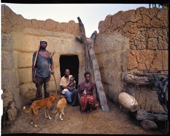Burkina Faso, province de Poni, pays des Lobi, Loropéni, paysan posant avec arc et flèches avec ses deux épouses et son fils devant leur maison