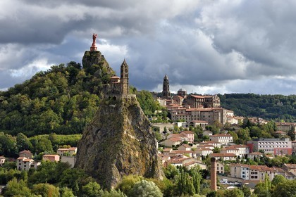 France, Haute Loire, Le Puy en Velay, Routes of Santiago de Compostela in France listed as World heritage by UNESCO, view of the city with the Saint-Michel d'Aiguilhe Chapel perched on a volcanic peak in the foreground, the Notre Dame de France statue (from 1860) on the Rocher Corneille overlooking the 12th century Notre Dame de l'Annonnement cathedral in the background