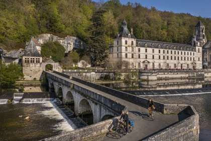 France, Dordogne, Brantome, cyclists traveling along the Flow Vélo cycle route crossing the Pont Coude (angled bridge) over Dronne River, Saint Pierre benedictine abbey in the background (aerial view)