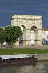 France, Charente-Maritime (17),  Saintonge, Saintes, l'arc de Germanicus est un arc routier en bordure de la Charente érigé en l'an 18-19 en l'honneur de l'empereur Tibère, son fils Drusus et son neveu et fils adoptif Germanicus, une gabarre au premier plan