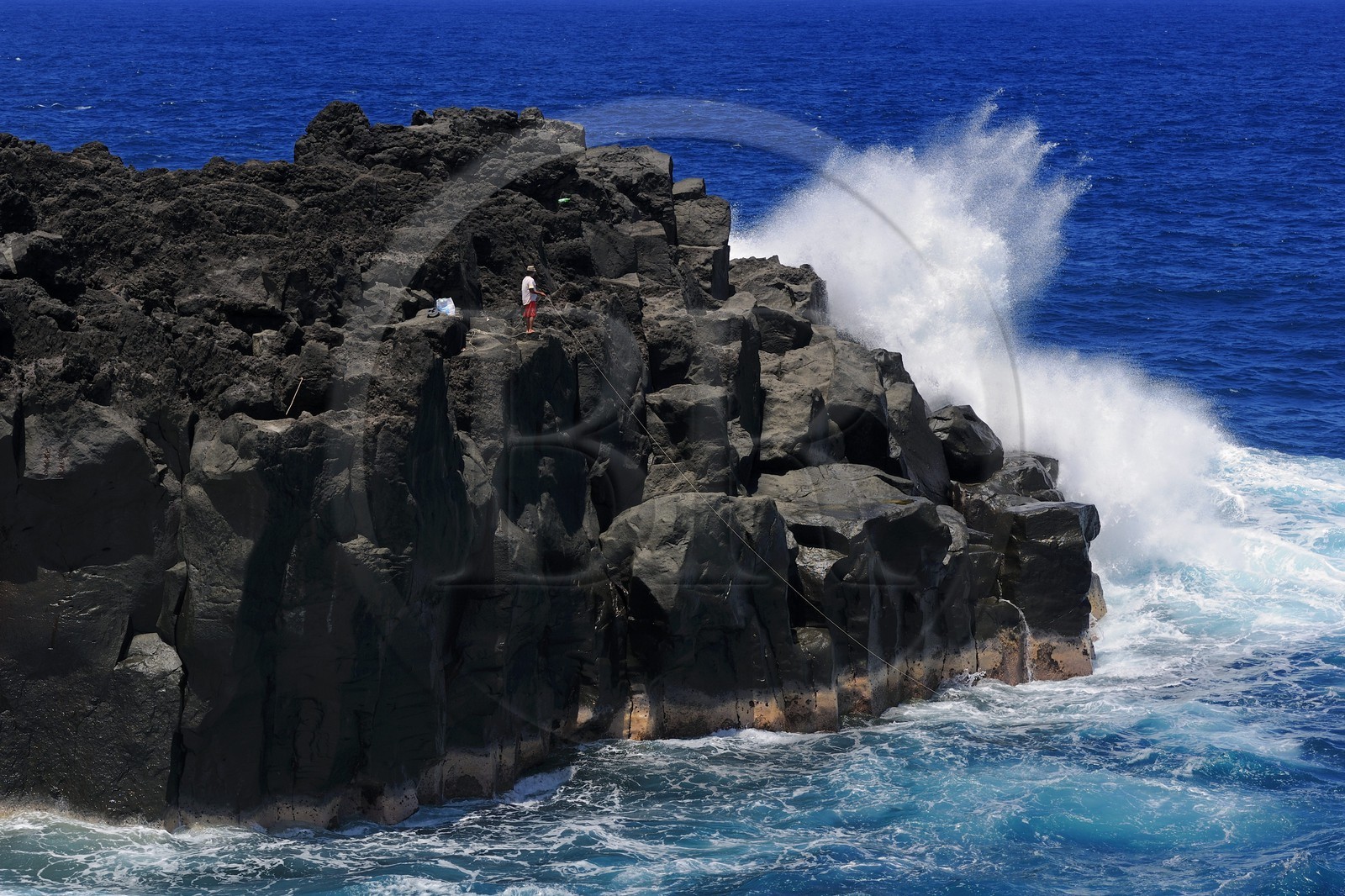 France, Ile de la Reunion, côte sud, Saint-Philippe, le Cap Méchant est situé le long d'une côte déchiquetée de roche volcanique frappée par la houle et typique de la région appelée Sud sauvage, pêcheur sur un rocher