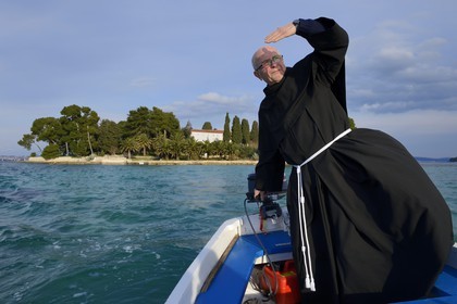Croatia, Dalmatia, Dalmatian Coast, Ugljan Island, Preko, Franciscan friar Bozo Susic leaving the Franciscan Monastery of the Galovac island on his boat