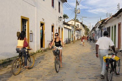 Brazil, Rio de Janeiro State, Paraty, colonial town founded in 1667 to export gold to Europe, cyclists in paved streets (Gold Route, Estrada Real)