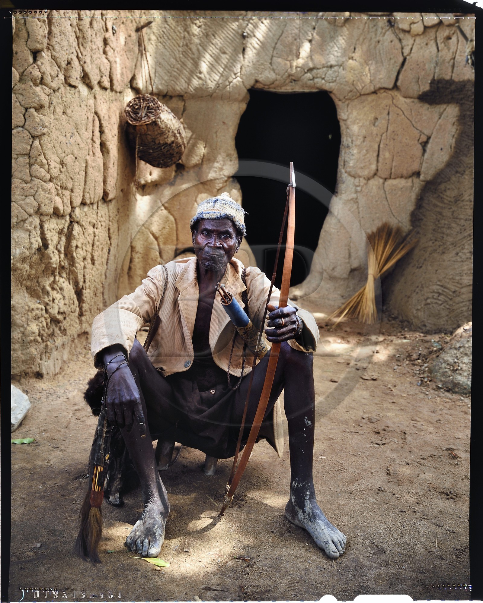 Burkina Faso, Poni province, Lobi land, Loropéni region, head of family posing with bow and arrows in front of the entrance of his house in the village of Lakar