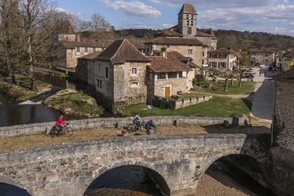 France, Dordogne, Périgord Vert, Saint Jean de Cole, labelled Les Plus Beaux Villages de France (The Most Beautiful Villages of France), cyclists on the Flow Vélo cycle route crossing the medieval bridge of the 12th century, the St. John the Baptist (Saint-Jean-Baptiste) church bell tower (aerial view)