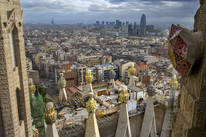 Espagne, Catalogne, Barcelone, quartier de l'Eixample, basilique de la Sagrada Familia de l'architecte du modernisme catalan Antoni Gaudi classée Patrimoine Mondial de l'UNESCO, sommets surmontés de mosaïques en forme de fruits entourant le chantier sur le toit de la nef à l'arrière de la future facade de la Gloire, la Torre Agbar de l'architecte Jean Nouvel en arrière plan