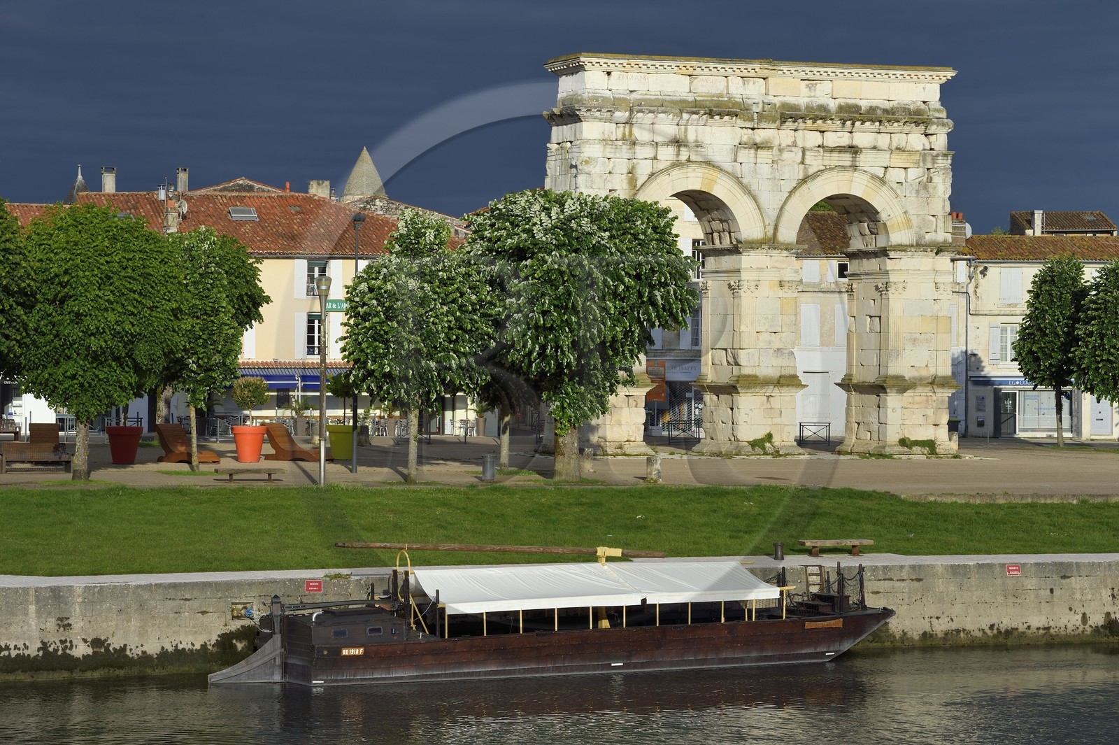 France, Charente-Maritime (17),  Saintonge, Saintes, l'arc de Germanicus est un arc routier en bordure de la Charente érigé en l'an 18-19 en l'honneur de l'empereur Tibère, son fils Drusus et son neveu et fils adoptif Germanicus, une gabarre au premier plan