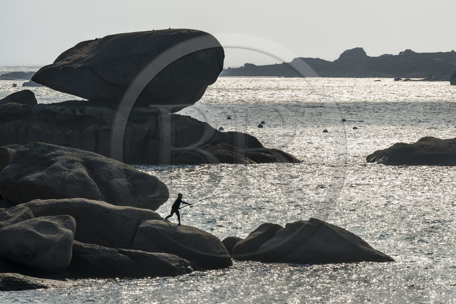 France, Côtes-d'Armor (22), Côte de Granit Rose, Trégastel, jeune pecheur à la ligne sur les rochers devant la plage de Ker ar Vir que longe le chemin de Grande Randonnée GR 34