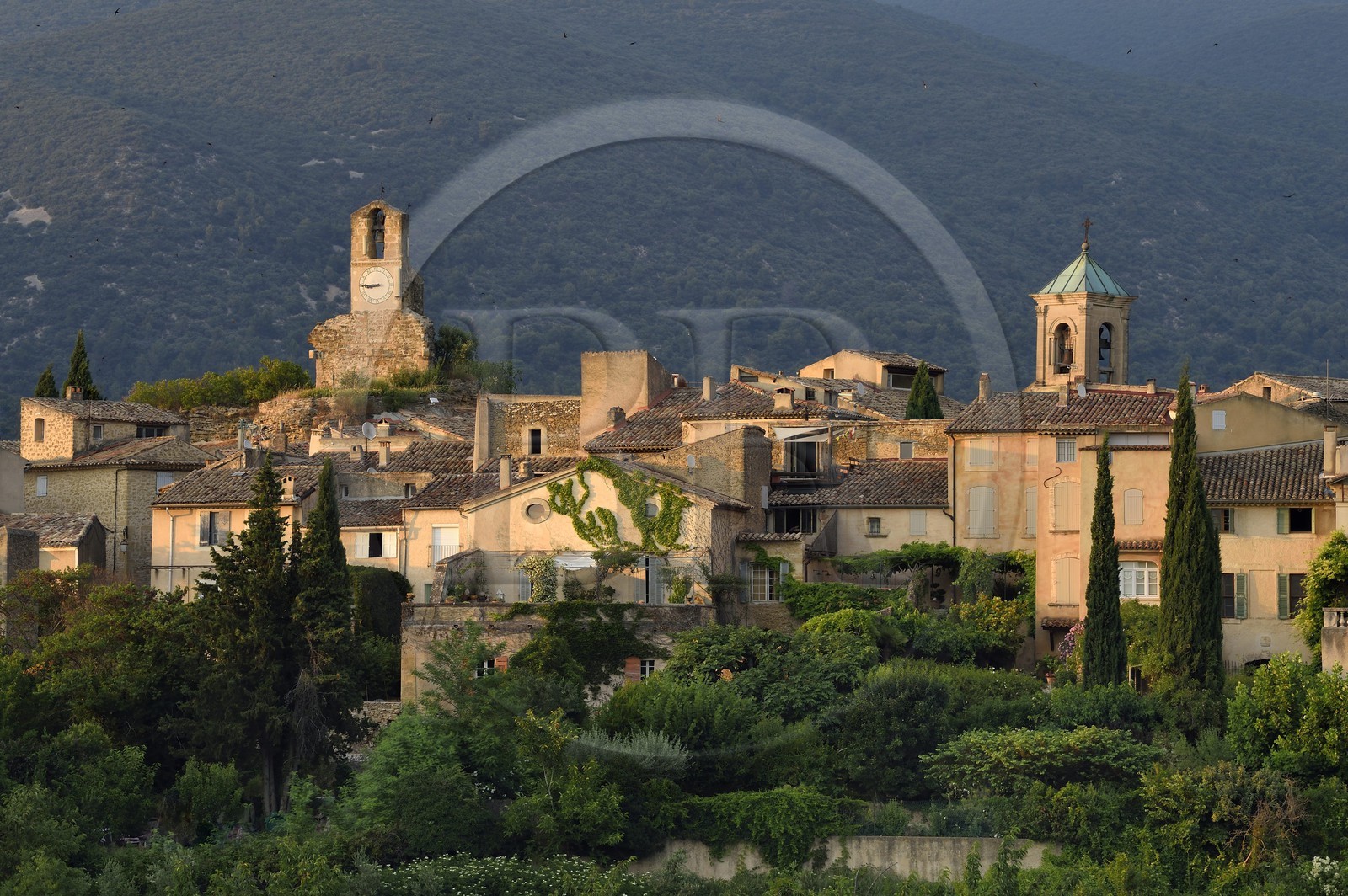 France, Vaucluse, Parc Naturel Regional du Luberon (Natural Regional Park of Luberon), Lourmarin, labelled Les Plus Beaux Villages de France (The Most Beautiful Villages of France), the clock tower and the  church bell tower, the massif of Luberon in background